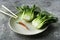 Baby bok choi halves on a plate on gray background