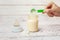 Baby bottle with milk formula on a white wooden background