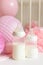 Baby bottles with breast milk with various festive paper decor and balloons in front of baby bedroom. It`s a girl or baby birthda
