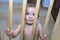 Baby boy behind the wooden safety gate of stairs