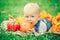 Baby boy with blue eyes in t-shirt and jeans romper lying on grass field meadow in yellow autumn leaves