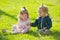 Baby boy and girl pick flowers on green grass. Brother and sister play with toy horse on sunny day. Kids Family. Future