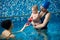Baby boy and his mother standing in paddling pool. Instructor woman playing with baby in pool during swimming classes