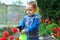 Baby boy irrigating flowers in colorful garden