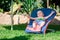 Baby boy lies on a deck-chair on green lawn