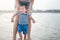 Baby boy making his first steps on the beach with his mother