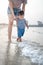 Baby boy making his first steps on the beach with his mother