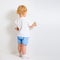 Baby boy with paint brush rear view standing near blank wall