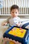 Baby boy playing with activity box in the bedroom while sitting on the floor