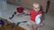 Baby boy playing alone in kitchen. Child take of chef hat sitting on floor