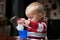 Baby boy playing with bottle and mug indoor