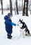 Baby boy plays with husky dogs. Winter