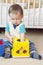 Baby boy plays nesting blocks at home against white bed