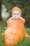 Baby boy in pumpkin costume with pumpkins
