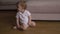 Baby boy sits on the floor in his family home house flat feeling sleepy and curious - Child wear white t-shirt body polo