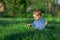 Baby boy sitting among green grass on spring lawn