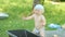 Baby boy sitting near basin in green garden. Beautiful baby smiling, hits the water rises and sets