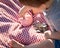 Baby Boy Sitting on Picnic Blanket Adds Coins into Piggy Bank