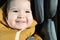 Baby boy smiles in a car seat. The sun is shining in the face. Close-up