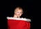 Baby boy smiling sitting in red basket with fur lining black background