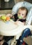 Baby boy with soother sitting in chair for feeding