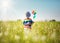 Baby boy standing in grass on the fieald with dandelions