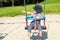 Baby boy on a swing on kids playground pointing somewhere