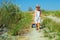 Baby boy walking the field path, dragging toy car