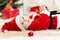 Baby boy weared Santa lying near Christmas tree