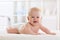 Baby boy wearing diaper in white sunny bedroom. Newborn child relaxing in bed