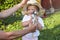 Baby chicken in hands of adult with child touching its feathers.