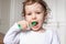 Baby child brush their teeth properly with a green toothbrush