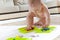 Baby child draws with colored paints hands, dirty feet. White list