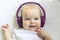 Baby child Toddler Happy smiling in a wireless purple headphones on a gray background. The concept of technology