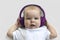 Baby child Toddler Happy smiling in a wireless purple headphones on a white background. The concept of technology learning from