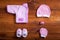 Baby clothes and accessories on brown wooden background table, pink child newborn fashion clothing set for girl, modern kid infant