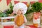 A baby in a cook`s hat sits back in a beautiful photo zone with flour and vegetables, a cook`s child, a child with flour and bre