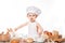 Baby cook sits on the table bread bread flour. Little baby chef with bread