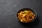 Baby Corn Manchurian dry looks like Schezwan Baby Corn in black bowl at dark slate background