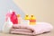 Baby cosmetic products, toys and towel on table against color