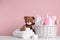 Baby cosmetic products in wicker basket, bath accessories and knitted toy bear on white table against background. Space for