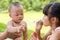 Baby curious to touch girls blowing soap bubbles