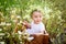 Baby with daisies in summer, baby sitting in a field with flowers