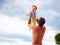 Baby delighted with happiness is thrown by dad up in the sky
