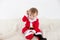 Baby disguised as santa claus with the hand on the face surrounded by toys