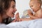 Baby drinking from bottle with mother smiling