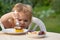 Baby eating cake. Little child eats cake in nature at a picnic. The concept of a happy sweet childhood.