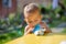 Baby eating fruit puree in pouch and close eves enjoying in front of the yellow table. close up, on the background is a