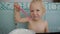 Baby eating yogurt making a mess. Portrait of laughing caucasian blue eyed baby girl eating yogurt.