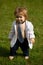 Baby fashion. Funny little business man in suit, jacket and necktie. Portrait of a little baby boy playing outdoor in